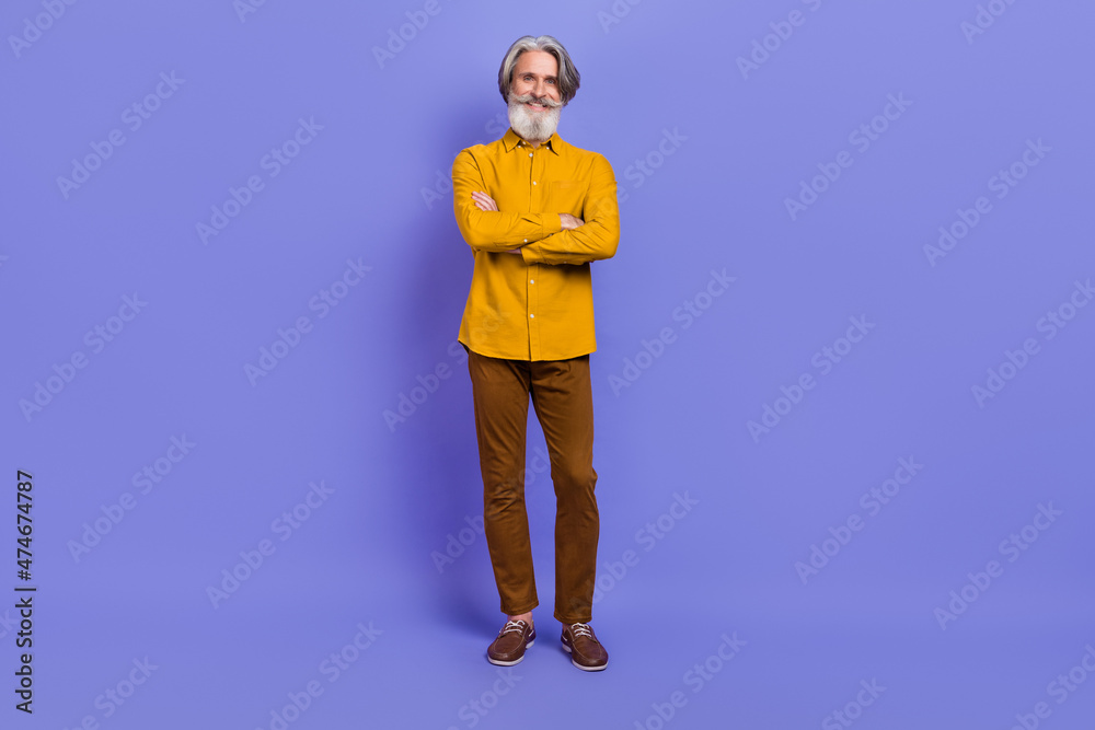Full length body size view of attractive cheery content gray-haired man folded arms isolated over bright violet purple color background Full length body size view of attractive cheery content gray-haired man folded arms isolated over bright violet purple color background