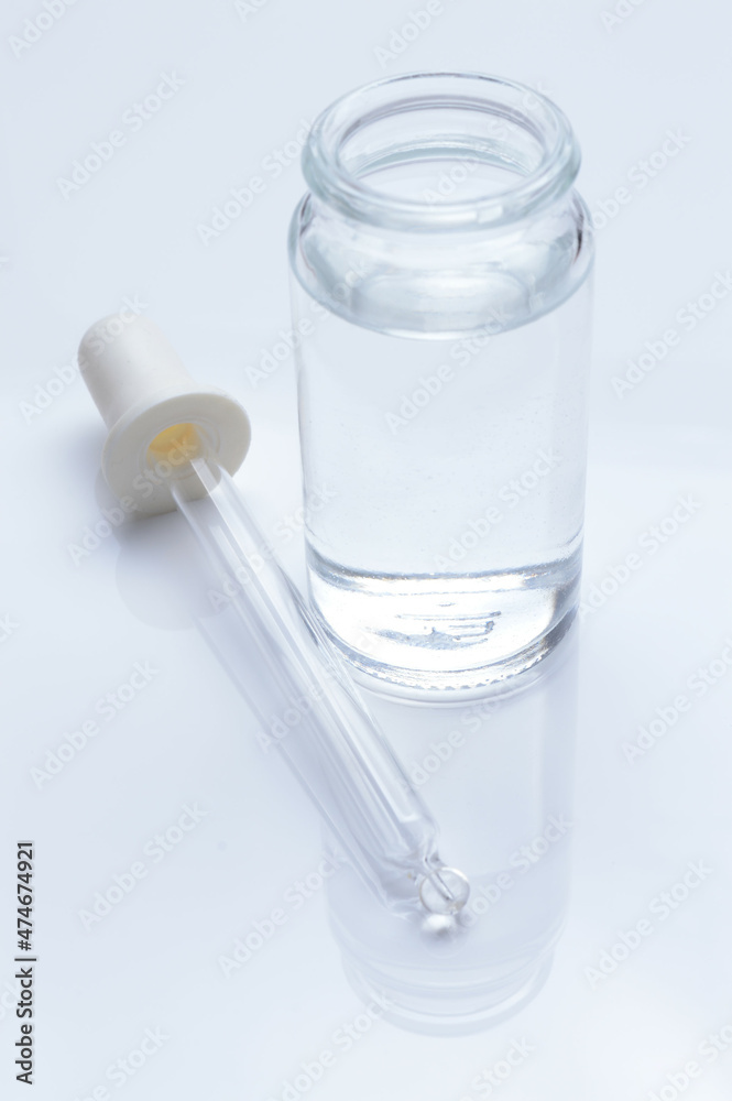 glass transparent jar and a cosmetic pipette with liquid droplets on a white background. glass transparent jar and a cosmetic pipette with liquid droplets on a white background.
