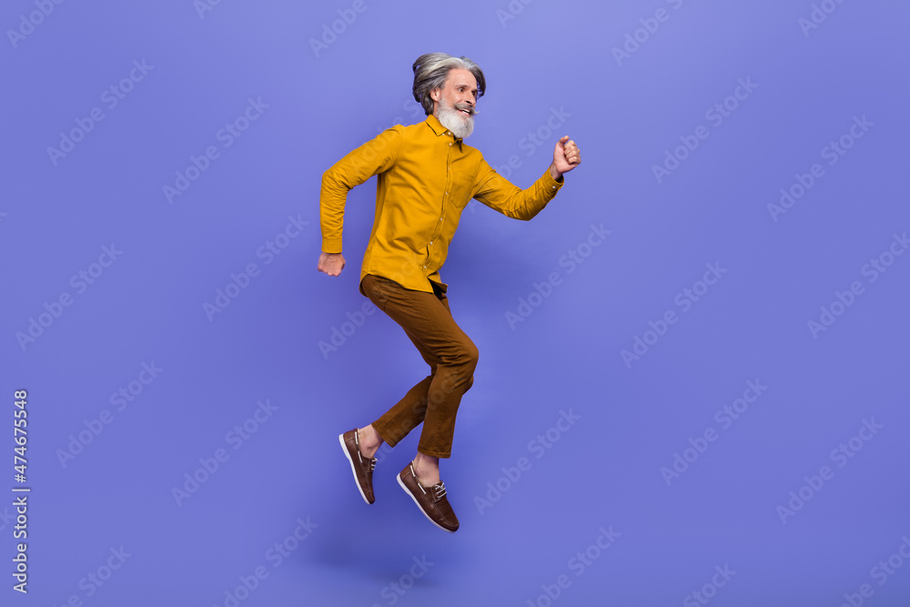 Full length body size view of attractive cheery gray-haired man jumping running motion isolated over bright violet purple color background