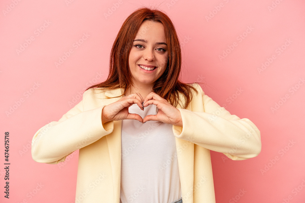 Young caucasian woman isolated on pink background smiling and showing a heart shape with hands. Young caucasian woman isolated on pink background smiling and showing a heart shape with hands.