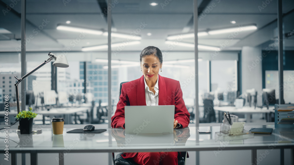 Successful Caucasian Businesswoman in Perfectly Stylish Suit Working on Laptop Computer on Top Floor Office Overlooking Big City. Female CEO Managing Company. Front View Shot Successful Caucasian Businesswoman in Perfectly Stylish Suit Working on Laptop Computer on Top Floor Office Overlooking Big City. Female CEO Managing Company. Front View Shot
