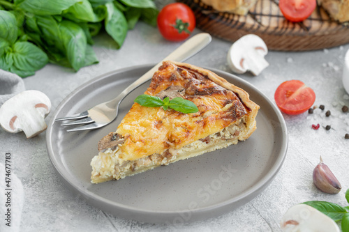 Quiche with mushrooms and chicken in a creamy filling on a gray concrete background. Copy space.