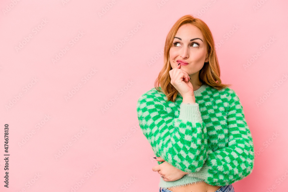 Young caucasian woman isolated on pink background relaxed thinking about something looking at a copy space. Young caucasian woman isolated on pink background relaxed thinking about something looking at a copy space.