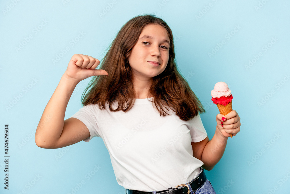 Little caucasian girl eating an ice cream isolated on blue background feels proud and self confident, example to follow. Little caucasian girl eating an ice cream isolated on blue background feels proud and self confident, example to follow.