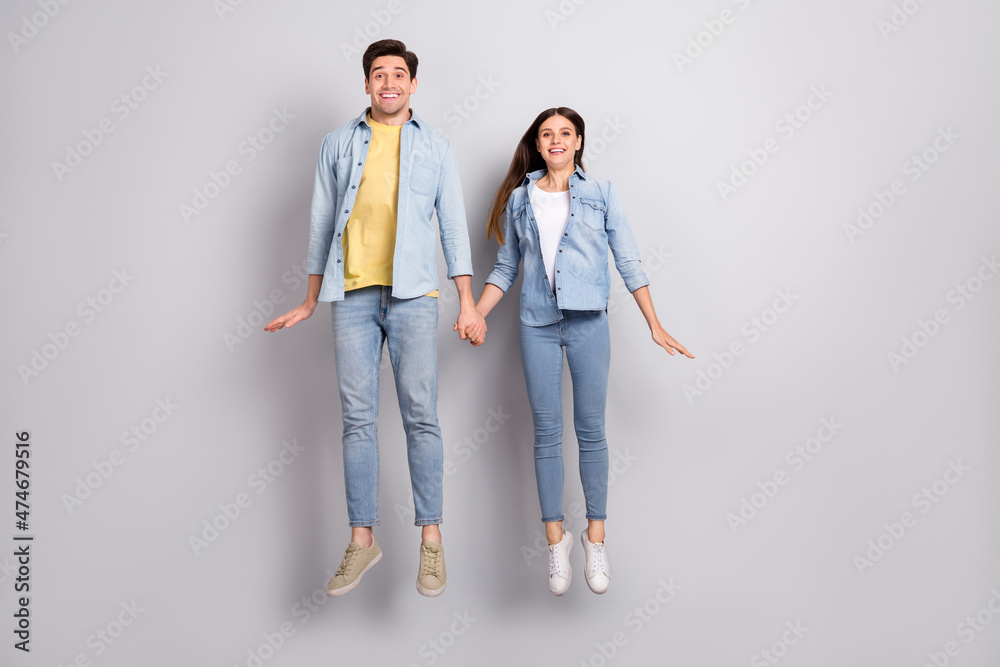 Photo of funny excited lady guy dressed denim shirts holding arms jumping high empty space isolated grey color background
