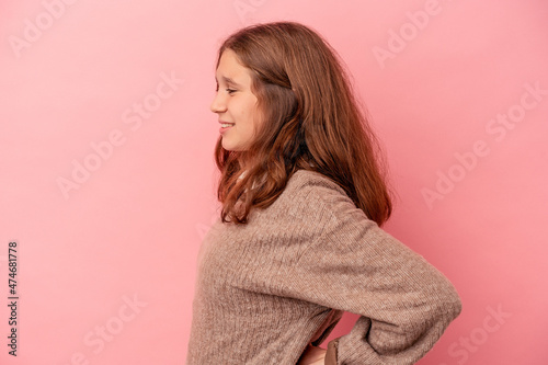 Little caucasian girl isolated on pink background suffering a back pain.