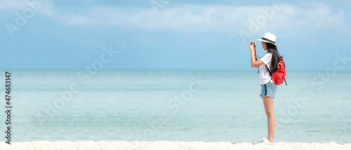 Happy traveler and tourism young women travel summer on the beach.  Asian people holding camera take photo  and relax outdoor destination and leisure trip travel in holiday
