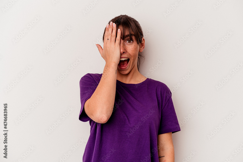 Young Argentinian woman isolated on white background having fun covering half of face with palm. Young Argentinian woman isolated on white background having fun covering half of face with palm.