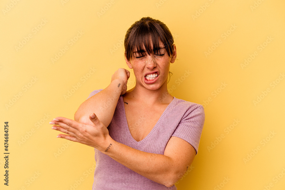 Obraz premium Young Argentinian woman isolated on yellow background massaging elbow, suffering after a bad movement.