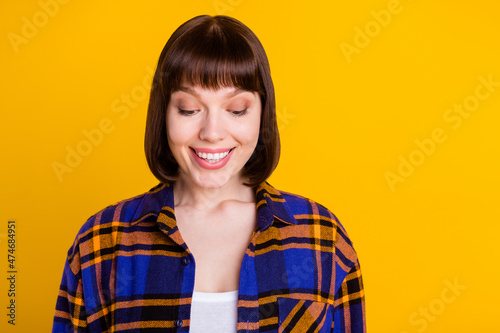 Portrait of attractive cheerful curious girl looking down reading good news isolated over bright yellow color background photo
