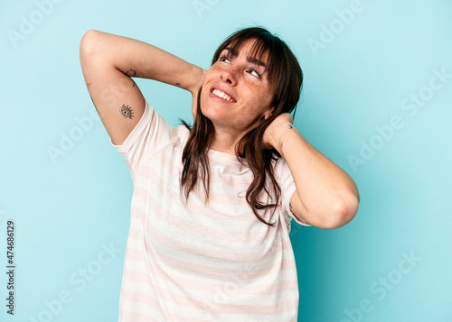 Young Argentinian woman isolated on blue background feeling confident, with hands behind the head.