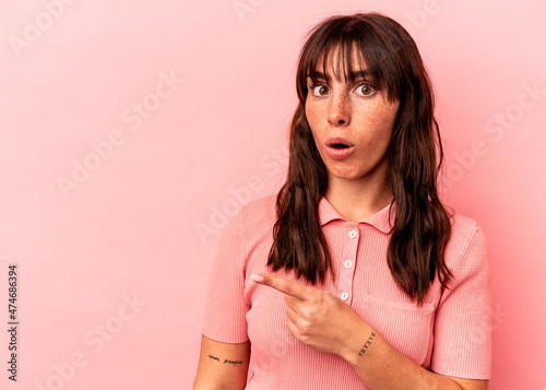 Young Argentinian woman isolated on pink background pointing to the side