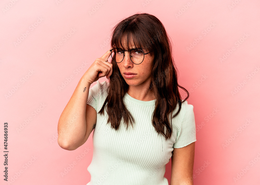 Young Argentinian woman isolated on pink background pointing temple with finger, thinking, focused on a task.