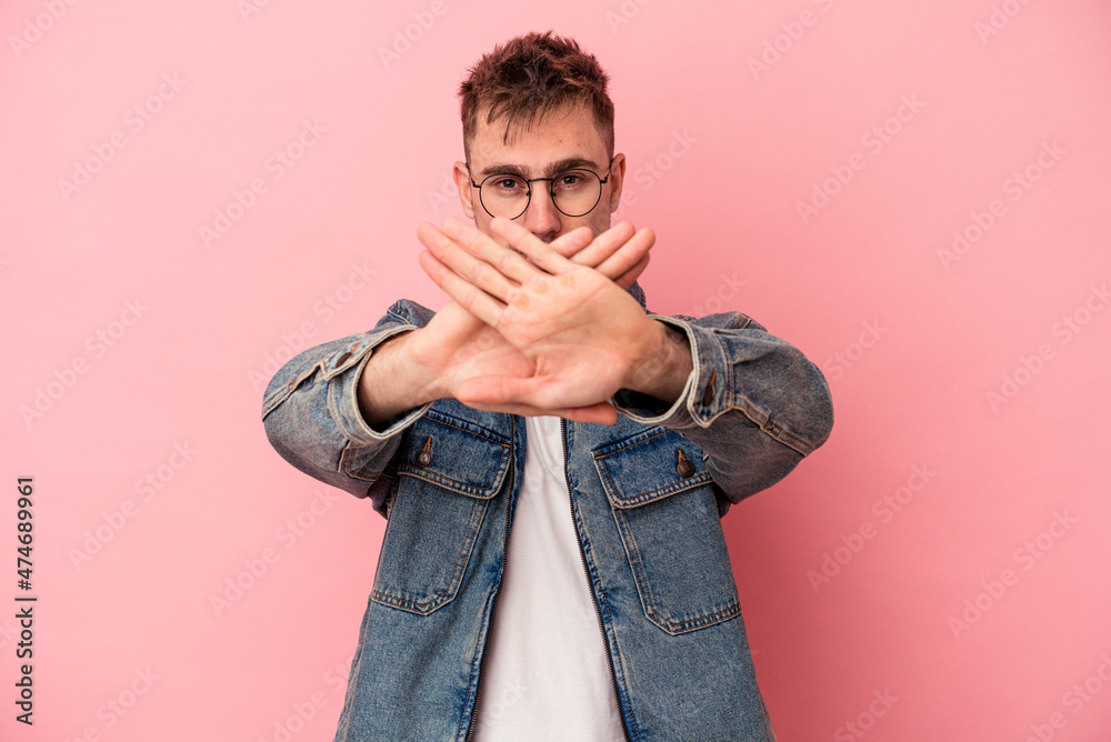 Obraz premium Young caucasian man isolated on pink background doing a denial gesture