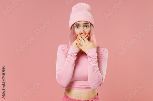 Young surprised amazed woman 20s with bright dyed rose hair in rosy top shirt hat cover mouth with hand isolated on plain light pastel pink background studio portrait People lifestyle fashion concept