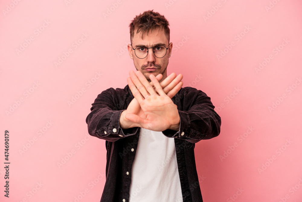 Obraz premium Young caucasian man isolated on pink background standing with outstretched hand showing stop sign, preventing you.