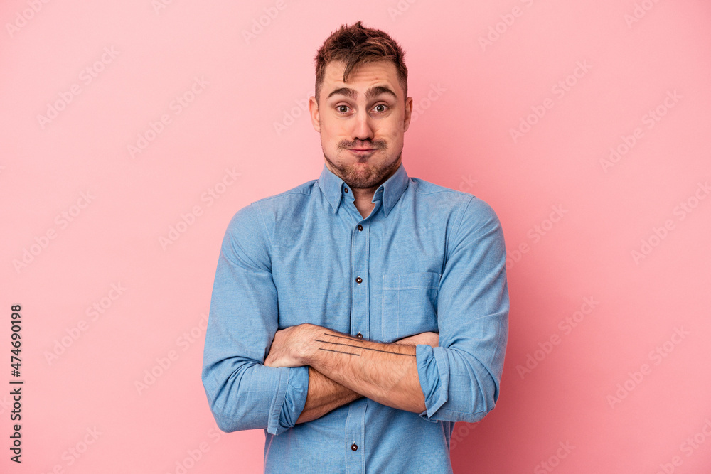 Young caucasian man isolated on pink background blows cheeks, has tired expression. Facial expression concept. Young caucasian man isolated on pink background blows cheeks, has tired expression. Facial expression concept.