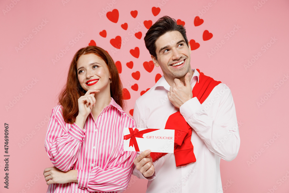 Young minded couple two friends woman man in casual shirt hold gift certificate coupon voucher card for store isolated on plain pastel pink background. Valentine's Day birthday holiday party concept Young minded couple two friends woman man in casual shirt hold gift certificate coupon voucher card for store isolated on plain pastel pink background. Valentine's Day birthday holiday party concept