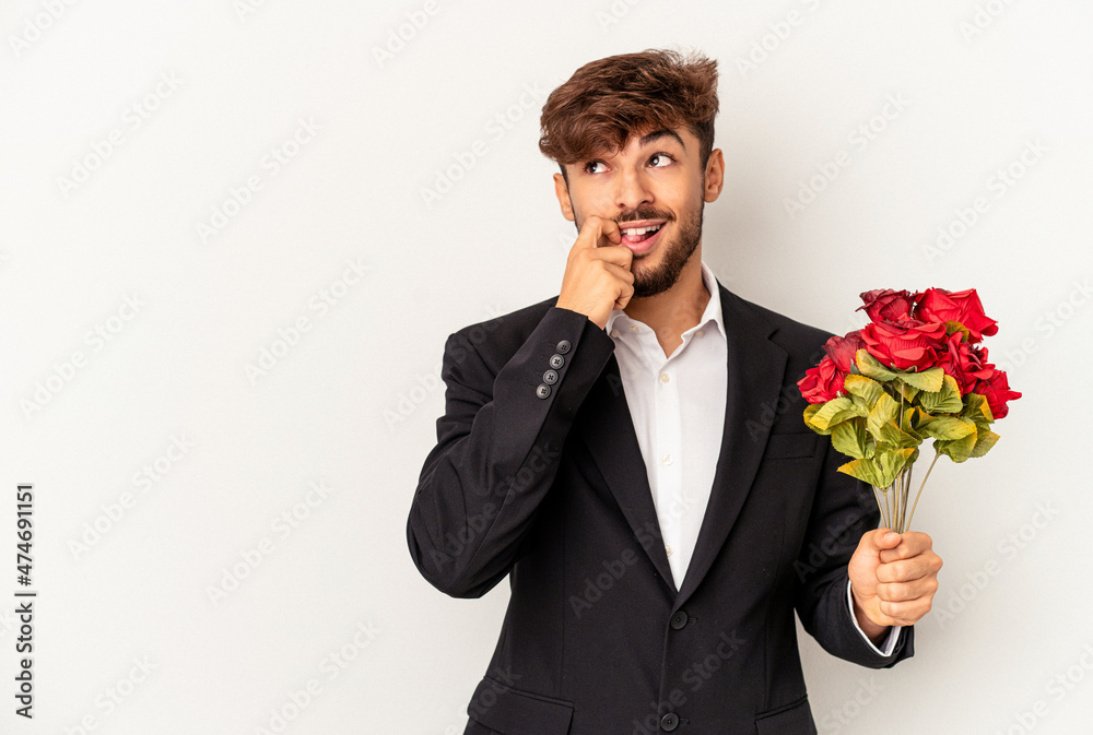 Young mixed race man holding bouquet of roses isolated on white background relaxed thinking about something looking at a copy space. Young mixed race man holding bouquet of roses isolated on white background relaxed thinking about something looking at a copy space.