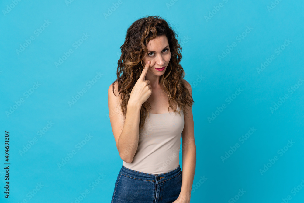 Young caucasian woman isolated on blue background showing something Young caucasian woman isolated on blue background showing something