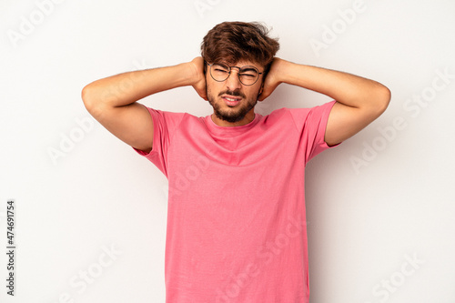 Young mixed race man isolated on grey background covering ears with hands.