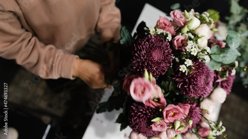 The florist's job is to decorate a large bouquet in a flower shop, close-up shot from above. Floral business concept.