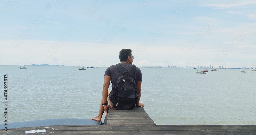 Asian tourist traveler man sitting relaxing on wooden pier on the seashore with blue sky fishing boats city skyline on background at Pattaya Thailand, Relaxation on vacation and travel
Asian tourist traveler man sitting relaxing on wooden pier on the seashore with blue sky fishing boats city skyline on background at Pattaya Thailand, Relaxation on vacation and travel