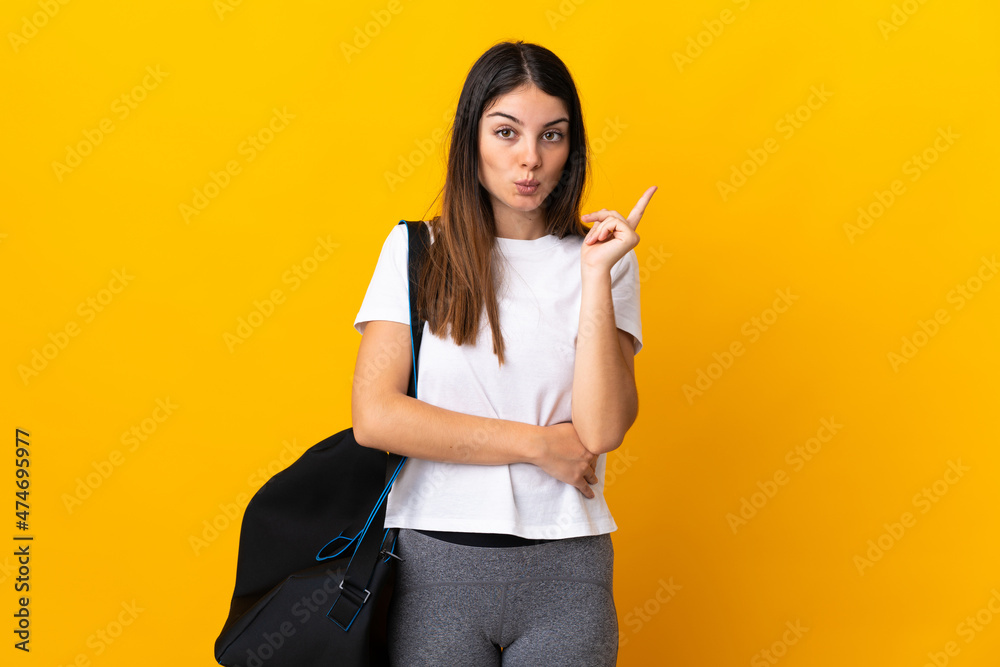 Young sport woman with sport bag isolated on yellow background intending to realizes the solution while lifting a finger up Young sport woman with sport bag isolated on yellow background intending to realizes the solution while lifting a finger up