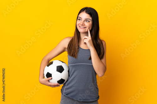 Young football player woman isolated on yellow background thinking an idea while looking up © luismolinero