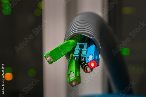 Fiber optic cables are in the corrugated tube. Several optical wires are in the background of the server room.