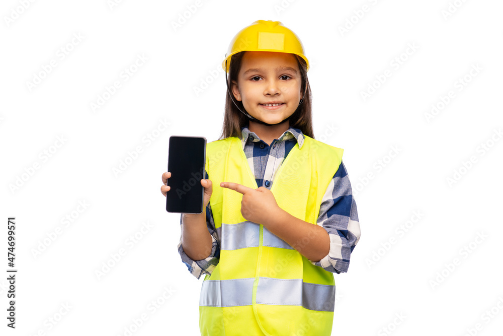 building, construction and profession concept - smiling little girl in protective helmet and safety vest with smartphone over white background