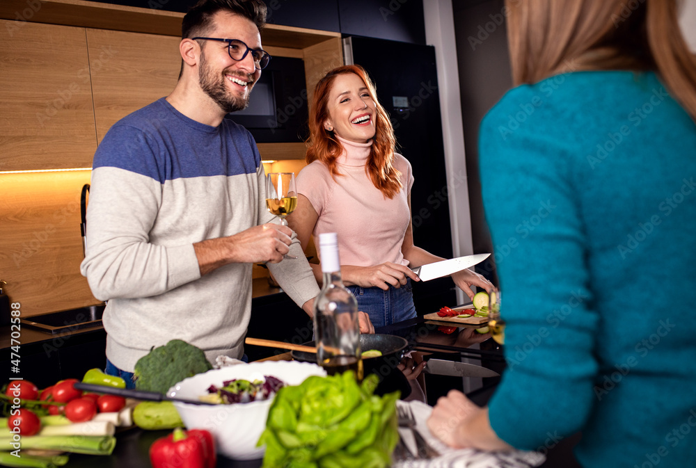Group of friends preparing vegetarian meal in a kitchen at home. Group of friends preparing vegetarian meal in a kitchen at home.