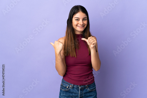 Young caucasian woman isolated on purple background pointing to the side to present a product