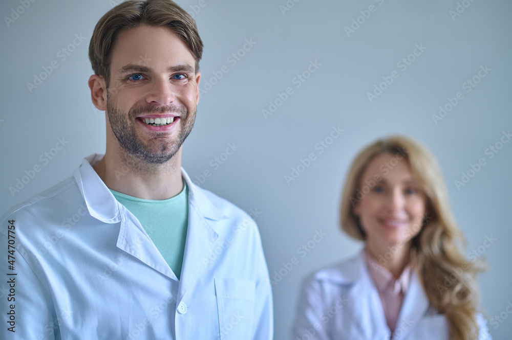 Man with toothy smile looking at camera and woman behind Man with toothy smile looking at camera and woman behind