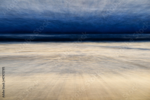 Photography Surging waves and grey steely skies spill onto the beach during the twilight hours