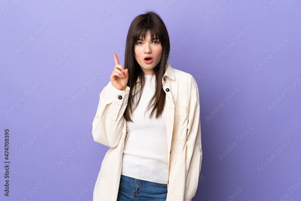 Young Ukrainian woman isolated on purple background intending to realizes the solution while lifting a finger up Young Ukrainian woman isolated on purple background intending to realizes the solution while lifting a finger up