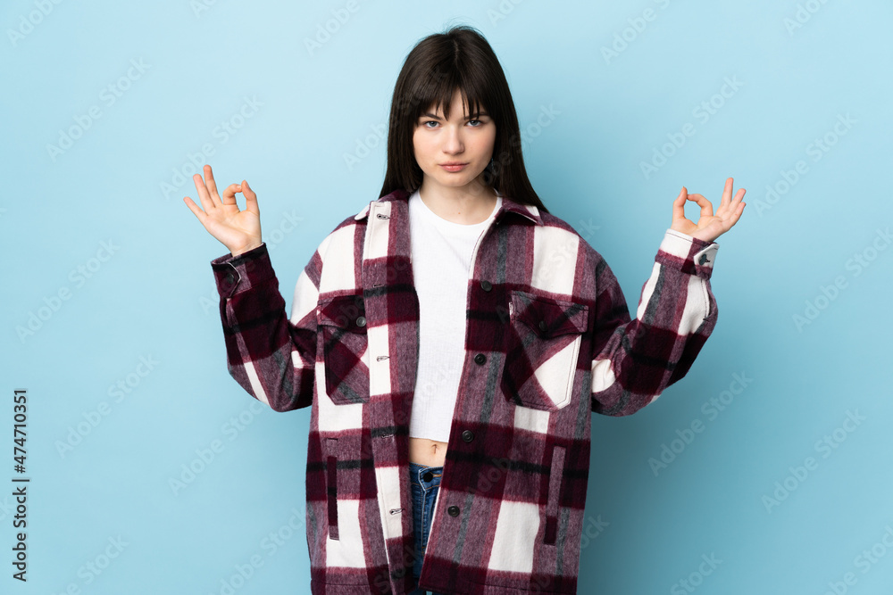 Teenager Ukrainian girl isolated on blue background in zen pose Teenager Ukrainian girl isolated on blue background in zen pose