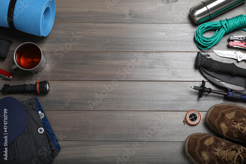 Flat lay composition with trekking poles and other hiking equipment on wooden background, space for text
