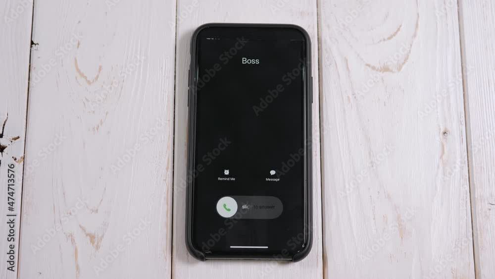 A close-up of an incoming call from the boss on a mobile phone screen ...