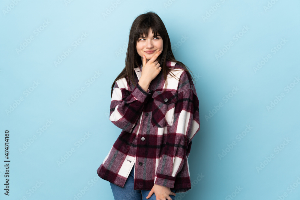 Teenager Ukrainian girl isolated on blue background thinking an idea while looking up Teenager Ukrainian girl isolated on blue background thinking an idea while looking up