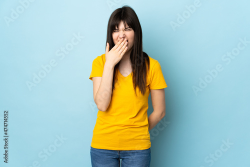 Teenager Ukrainian girl isolated on blue background happy and smiling covering mouth with hand