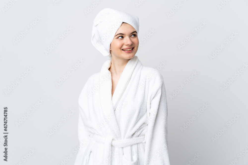 Teenager girl in a bathrobe isolated on white background looking up while smiling Teenager girl in a bathrobe isolated on white background looking up while smiling