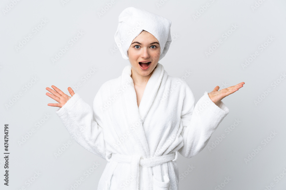 Teenager girl in a bathrobe isolated on white background with shocked facial expression