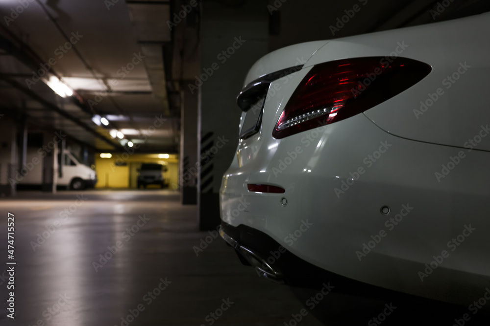 White car in parking garage, closeup. Space for text
