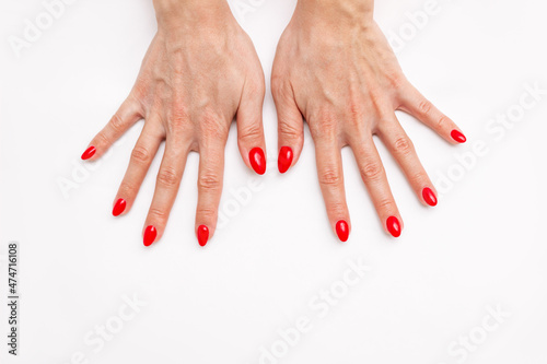 Top view of a woman's hands with a perfect professional bright red manicure on a white background. Red Nail polish