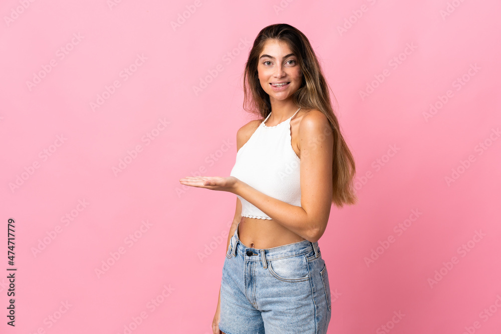 Young caucasian woman isolated on pink background presenting an idea while looking smiling towards Young caucasian woman isolated on pink background presenting an idea while looking smiling towards