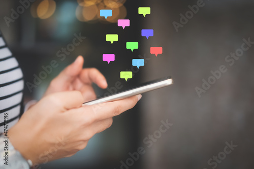 Woman hand using smart phone with chat icon graphic at coffee shop abstract background. Technology business and freelance concept.