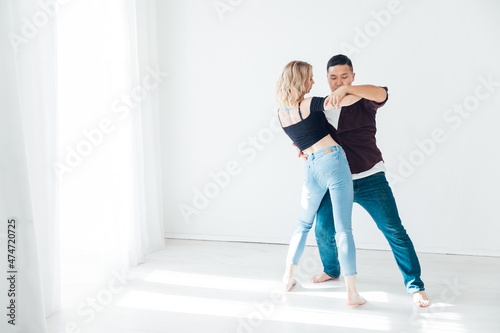 a woman and a man dancing to the music of a bachata in a white hall