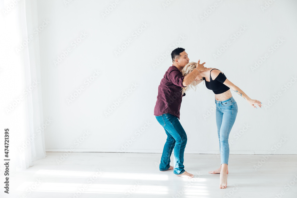 a woman and a man dancing to the music of a bachata in a white hall a woman and a man dancing to the music of a bachata in a white hall