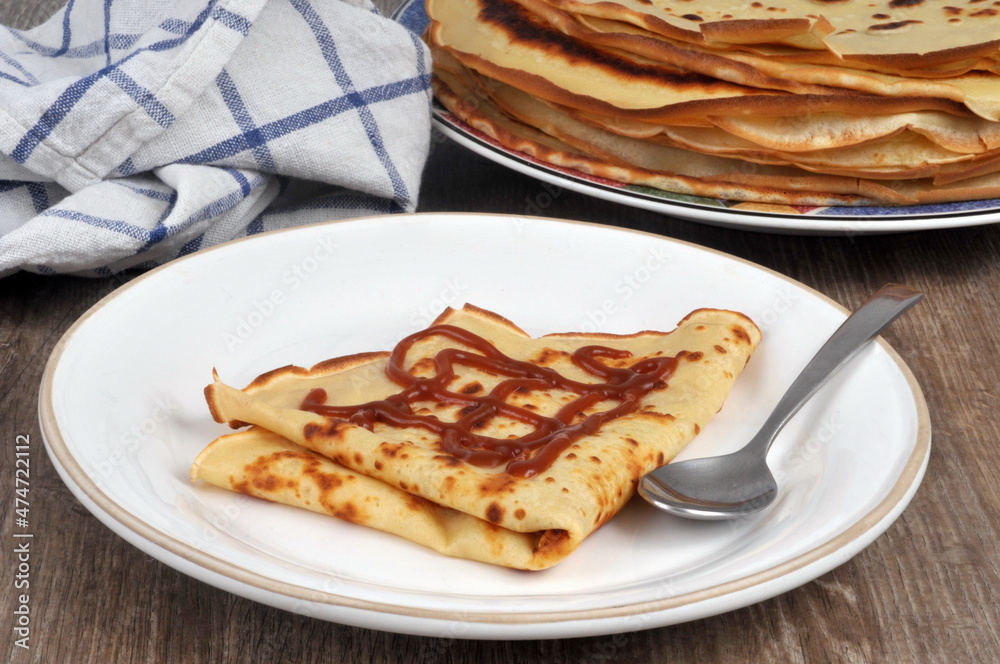 Crêpe avec du caramel au beurre salé servie dans une assiette avec une cuillère Crêpe avec du caramel au beurre salé servie dans une assiette avec une cuillère